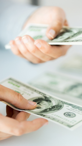 Pair of hands with one handing cash to the other.