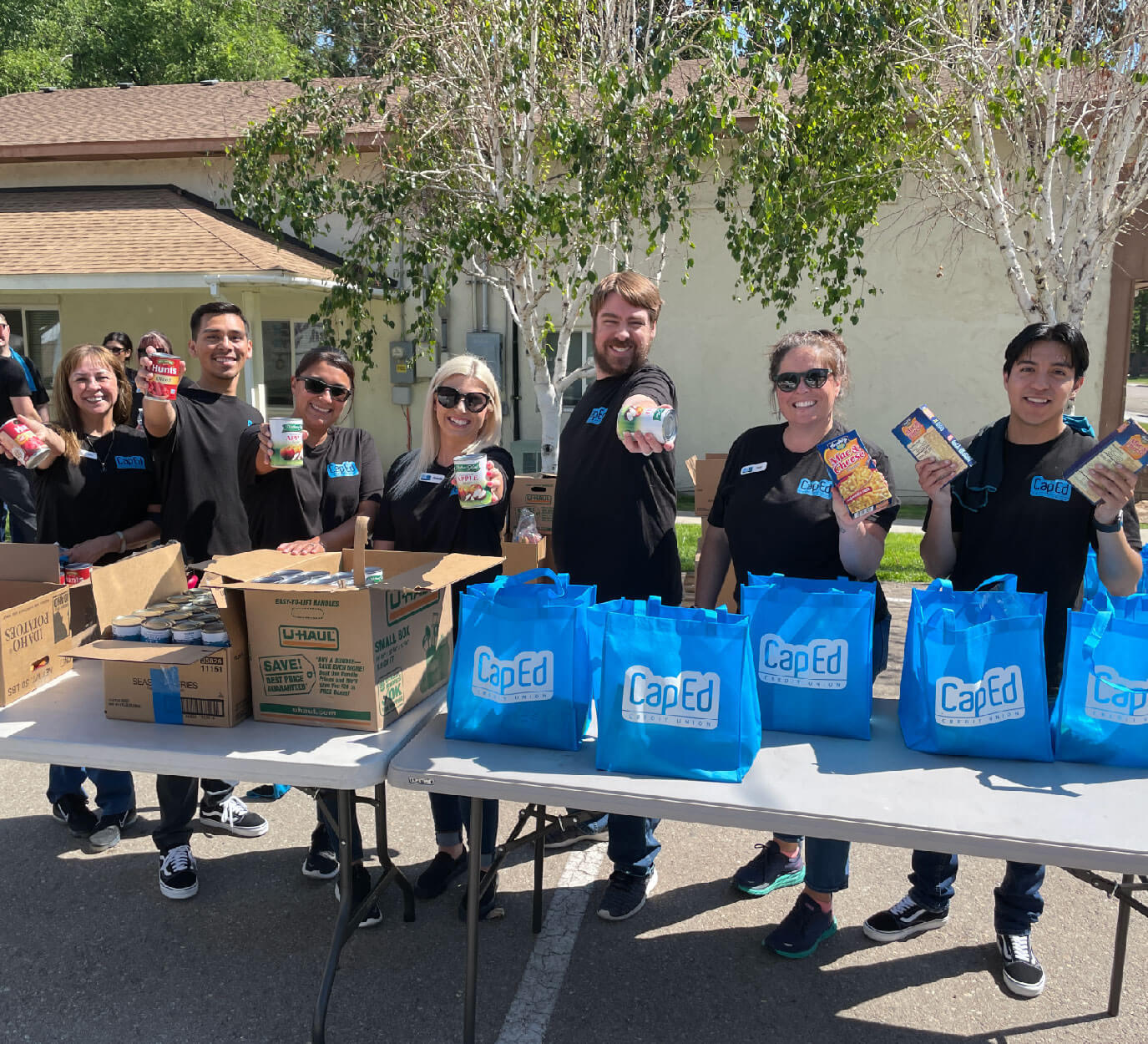 CapEd team members giving out canned food at a traveling table food drive.