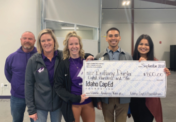 A group of educators receiving a teacher grant donation from the Idaho CapEd Foundation in the form of a giant check.
