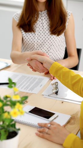 Two people discussing the advantages of a home refinance and shaking hands.