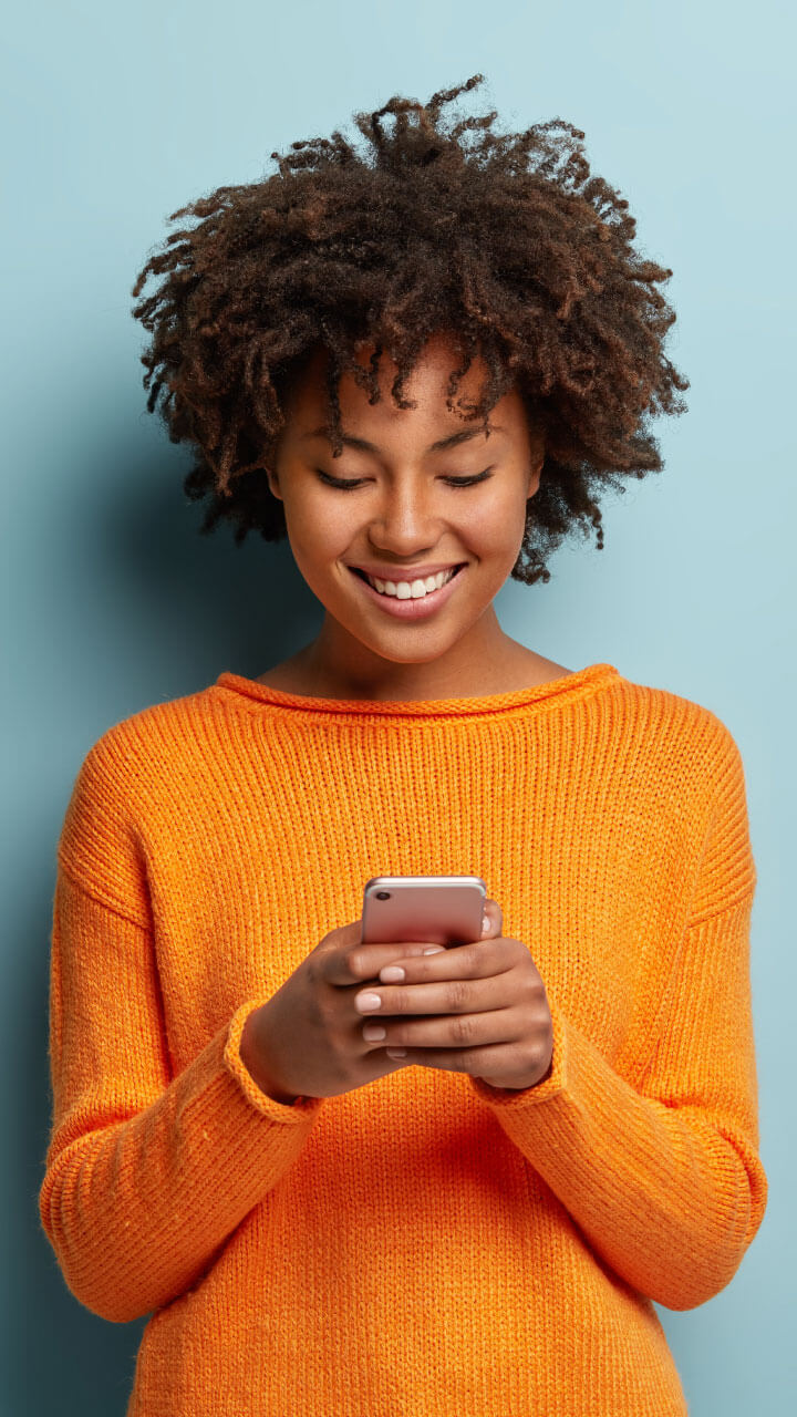 Woman smiling and checking account information on a phone.